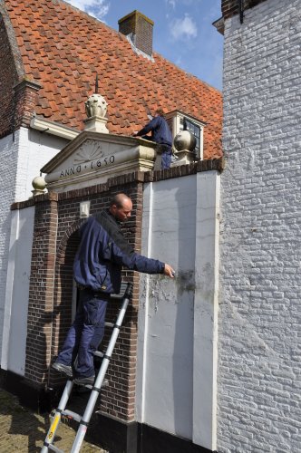 Monumentenwachter staat op een ladder en inspecteert het monument